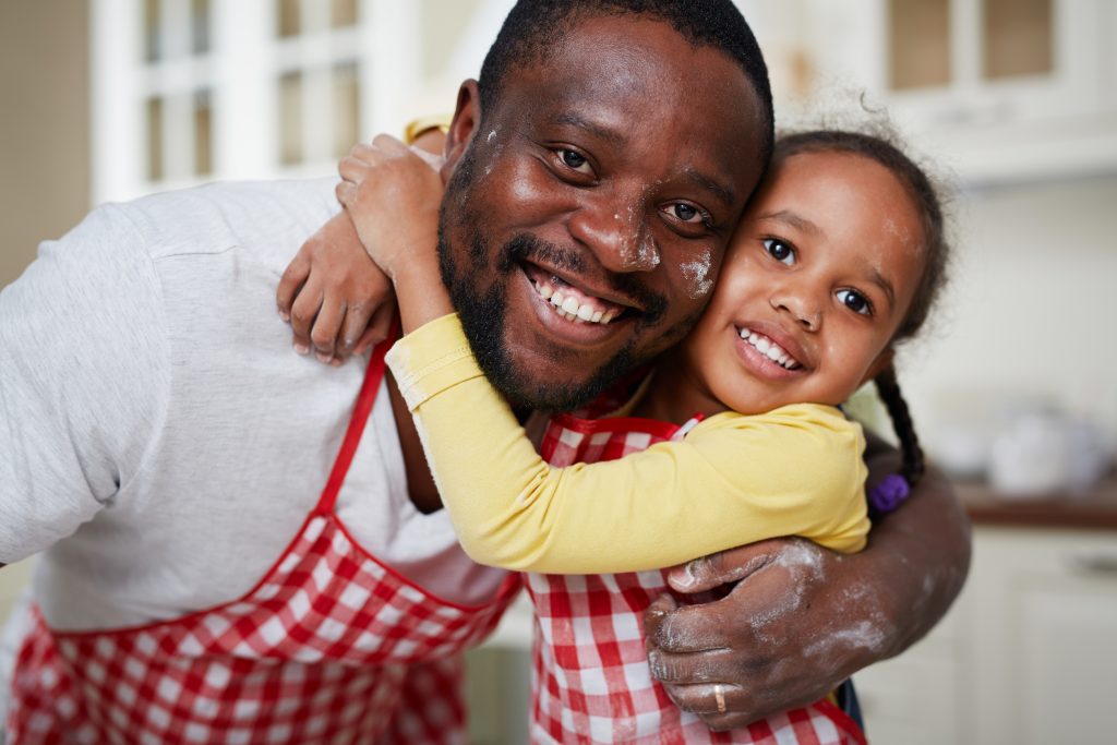 Adorable girl and her father embracing in the kitchen